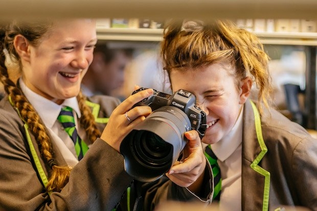 Two girls, one looking through camera lens